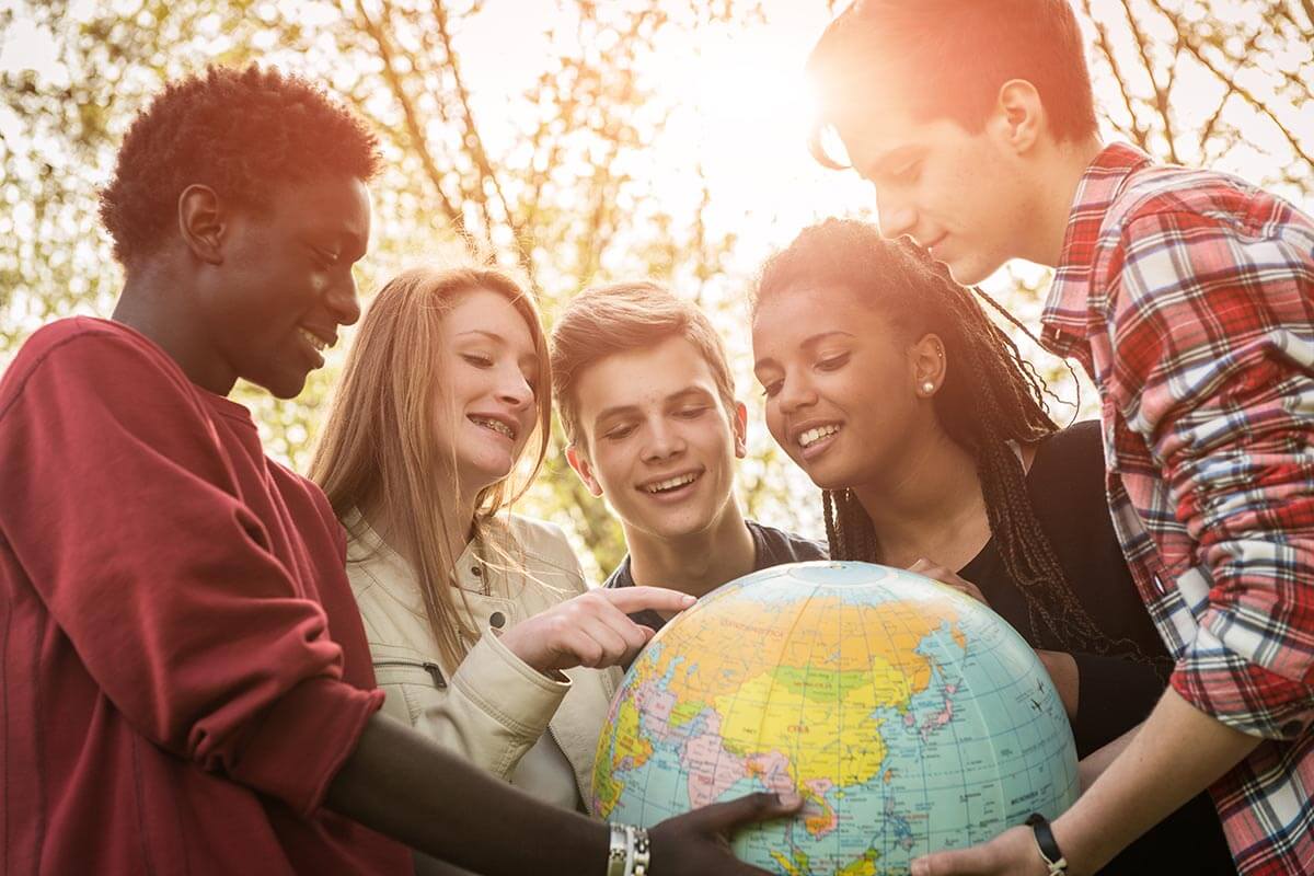 Gruppe Jugendliche schaut auf Globus