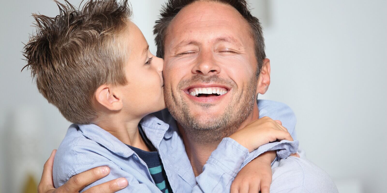 Ein Mann wird von seinem Sohn auf die Wange geküsst.