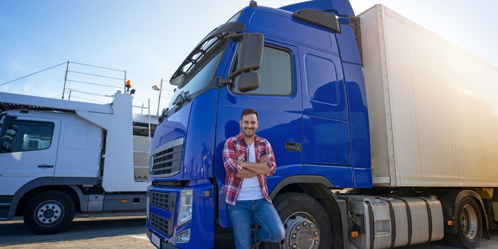 Kaufmann für Spedition und Logistikdienstleistung steht an einen LKW gelehnt. 