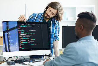Zwei Fachinformatiker für Daten- und Prozessanalyse diskutieren an einem Computer.